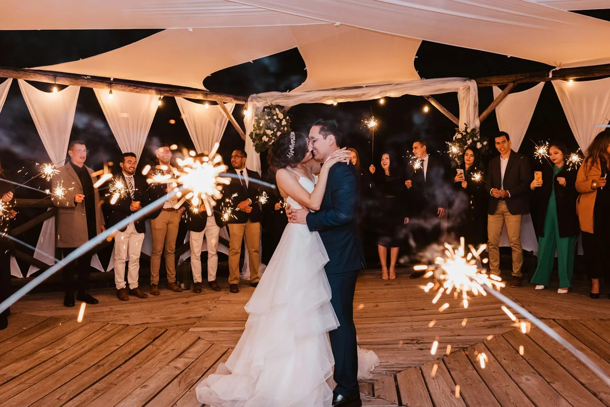 Newlyweds surrounded by guests holding sparklers