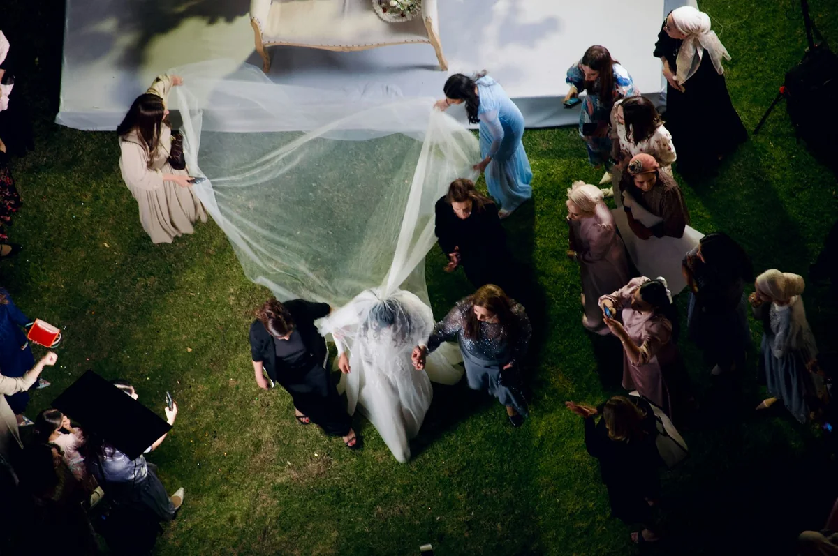 Wedding guests helping carry the bridal veil